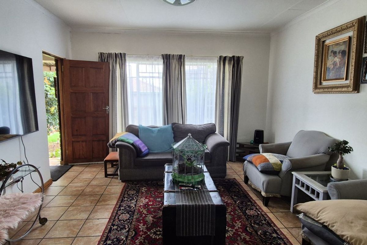 A comfortable living room featuring tiled flooring, large windows allowing natural light, and direct access to the exterior.