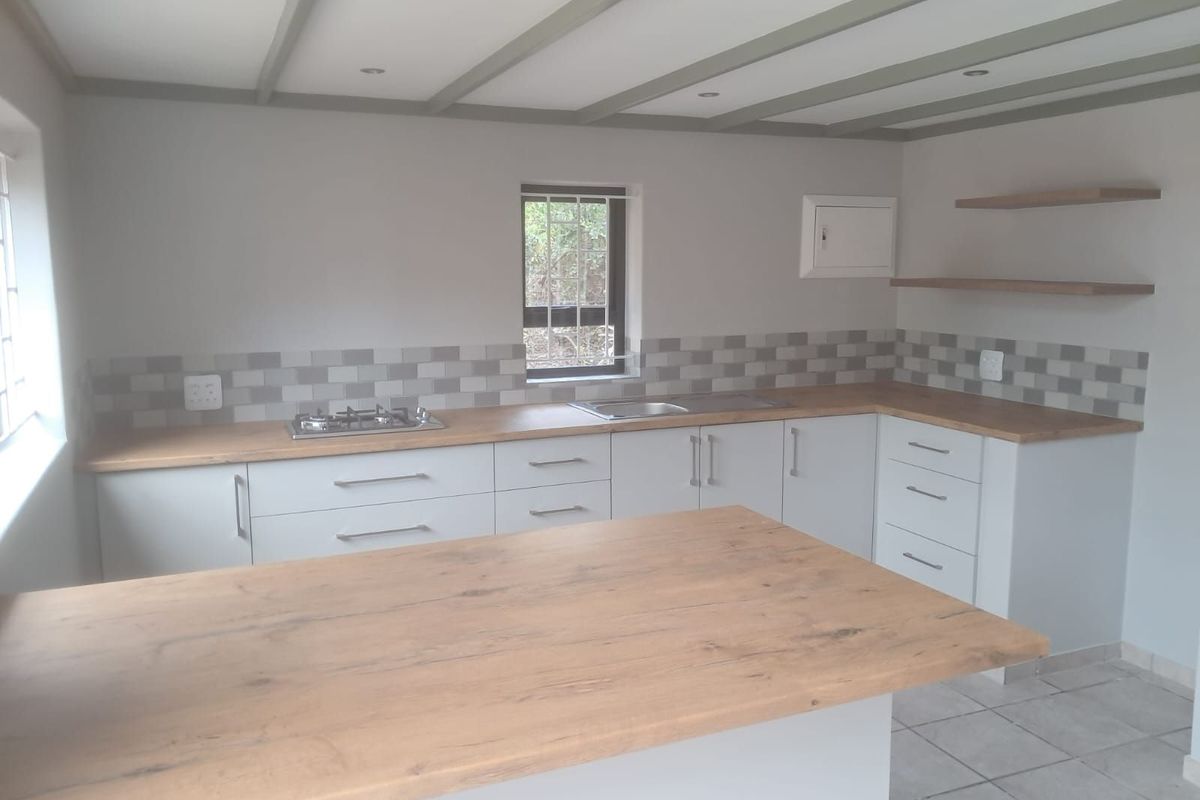 Modern kitchen featuring light cabinetry, wood-look countertops, a built-in gas hob, stainless steel sink, and tiled backsplash with open shelving.