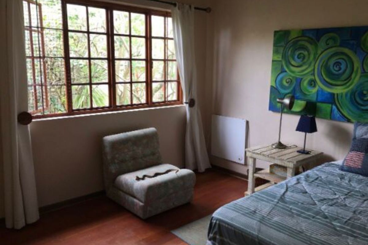 A bedroom featuring wooden flooring, a large multi-pane window with timber frames, and a wall-mounted electric panel heater.