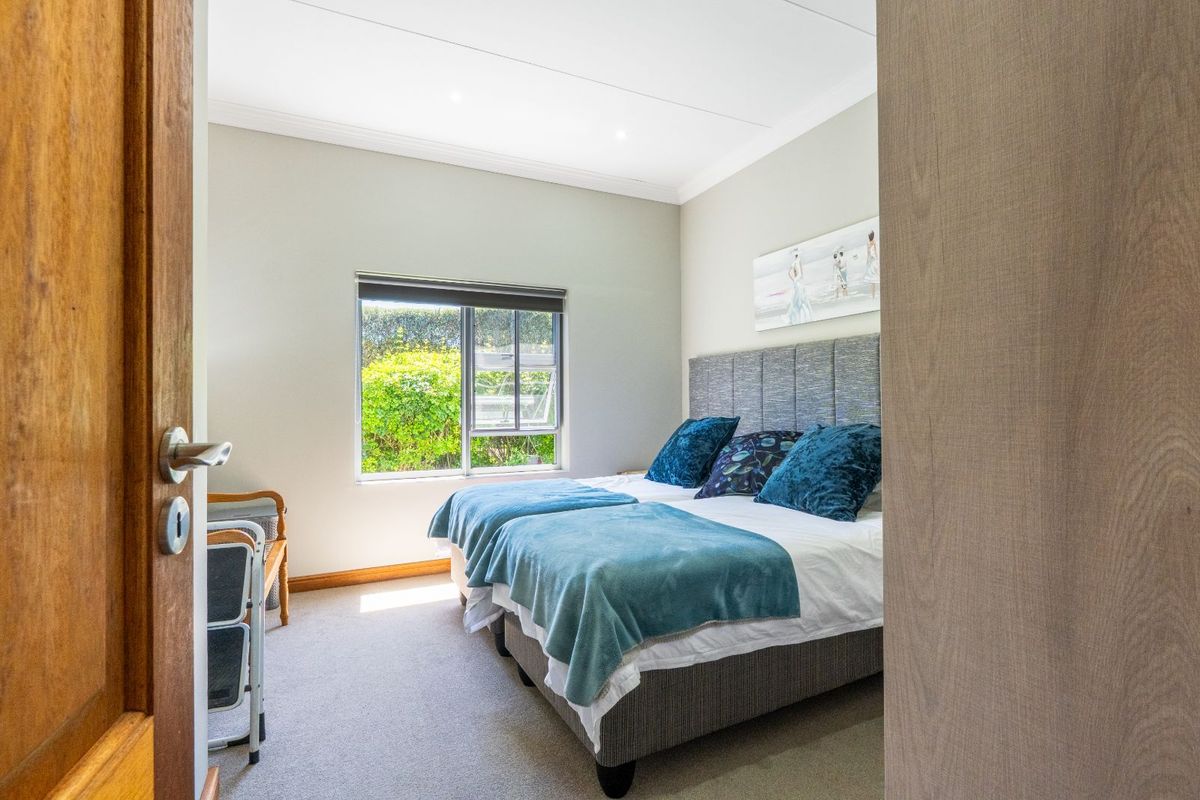 A well-maintained bedroom featuring neutral carpeting, recessed ceiling lighting, and a large window providing natural light and garden views.
