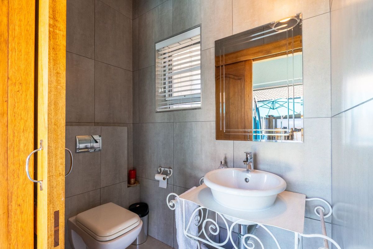 A modern bathroom featuring large-format grey wall tiles, a wall-mounted toilet with a concealed cistern, and a vessel sink vanity.