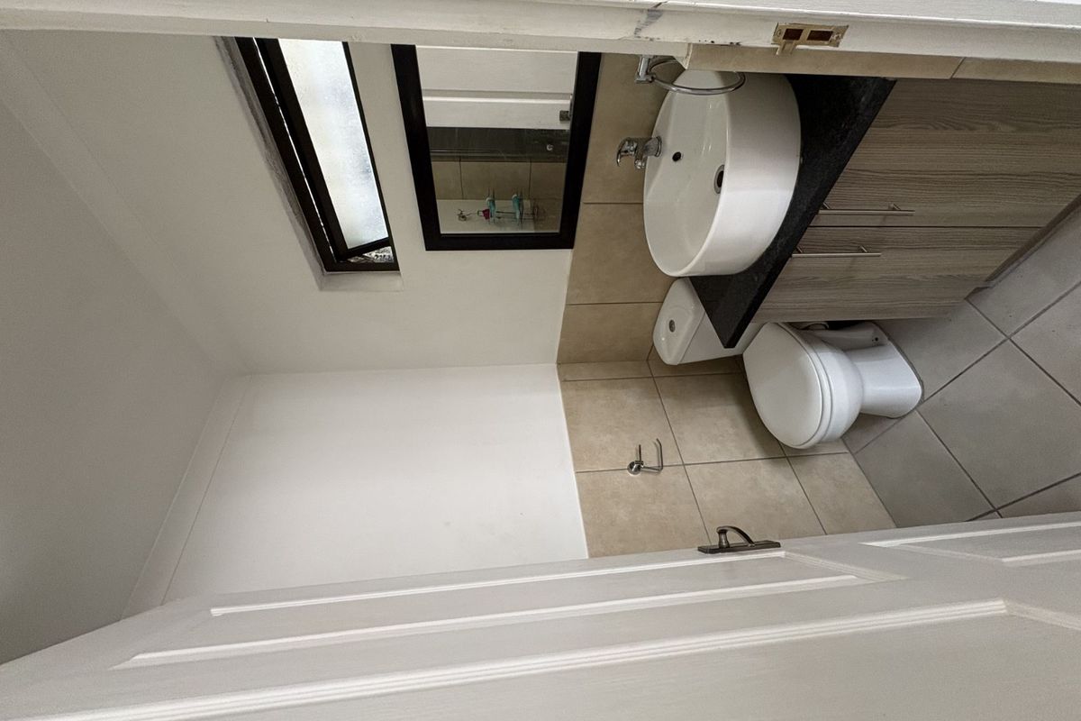 A compact bathroom featuring a modern vessel sink vanity, a standard toilet, and tiled flooring with a small window for natural light.