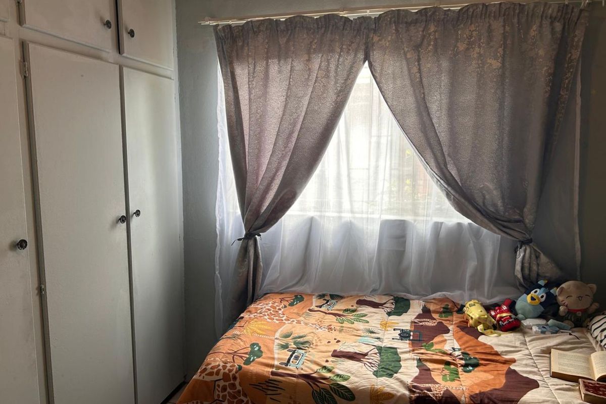 A bedroom featuring built-in storage cupboards and a window with natural light.