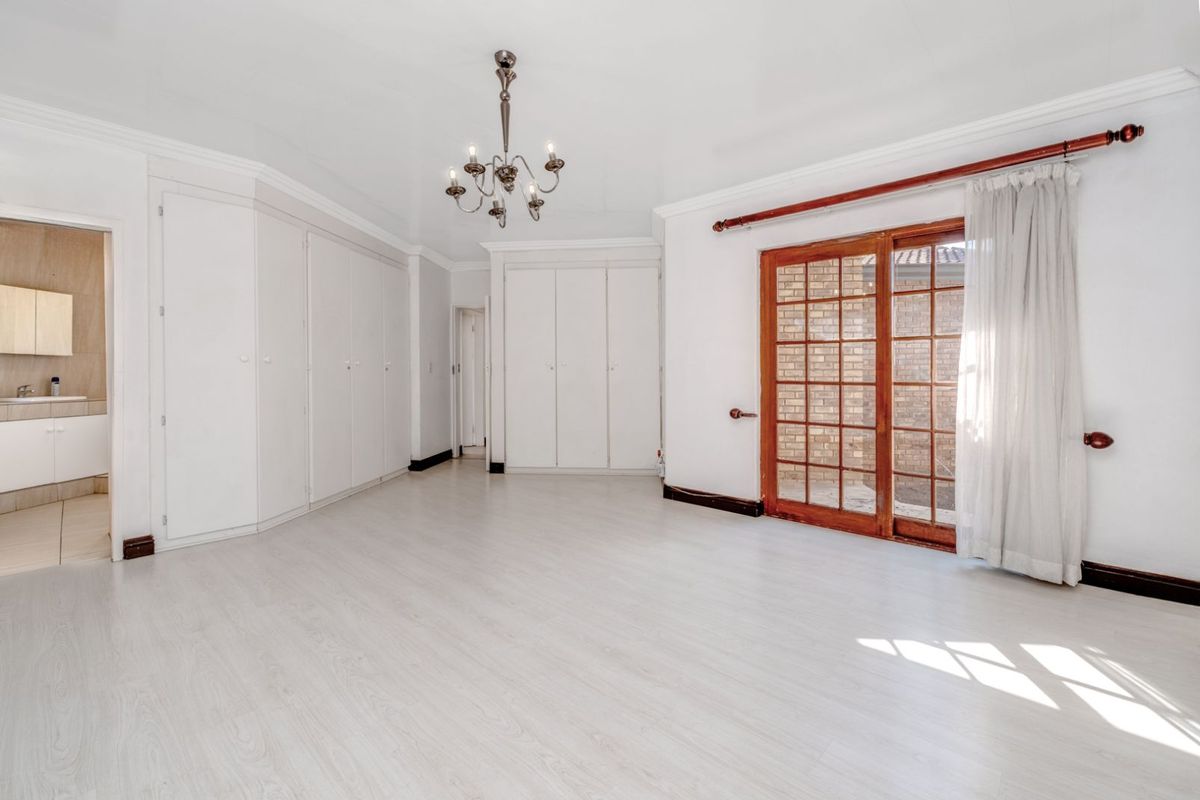 Spacious bedroom featuring extensive built-in cabinetry, light wood-look flooring, and sliding glass doors providing direct access to the exterior.