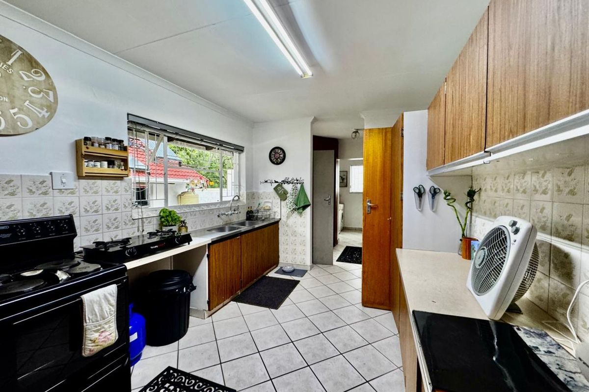 Functional kitchen featuring wood-finish cabinetry, tiled flooring, double stainless steel sink, and built-in gas stove, offering a practical layout for daily meal preparation.