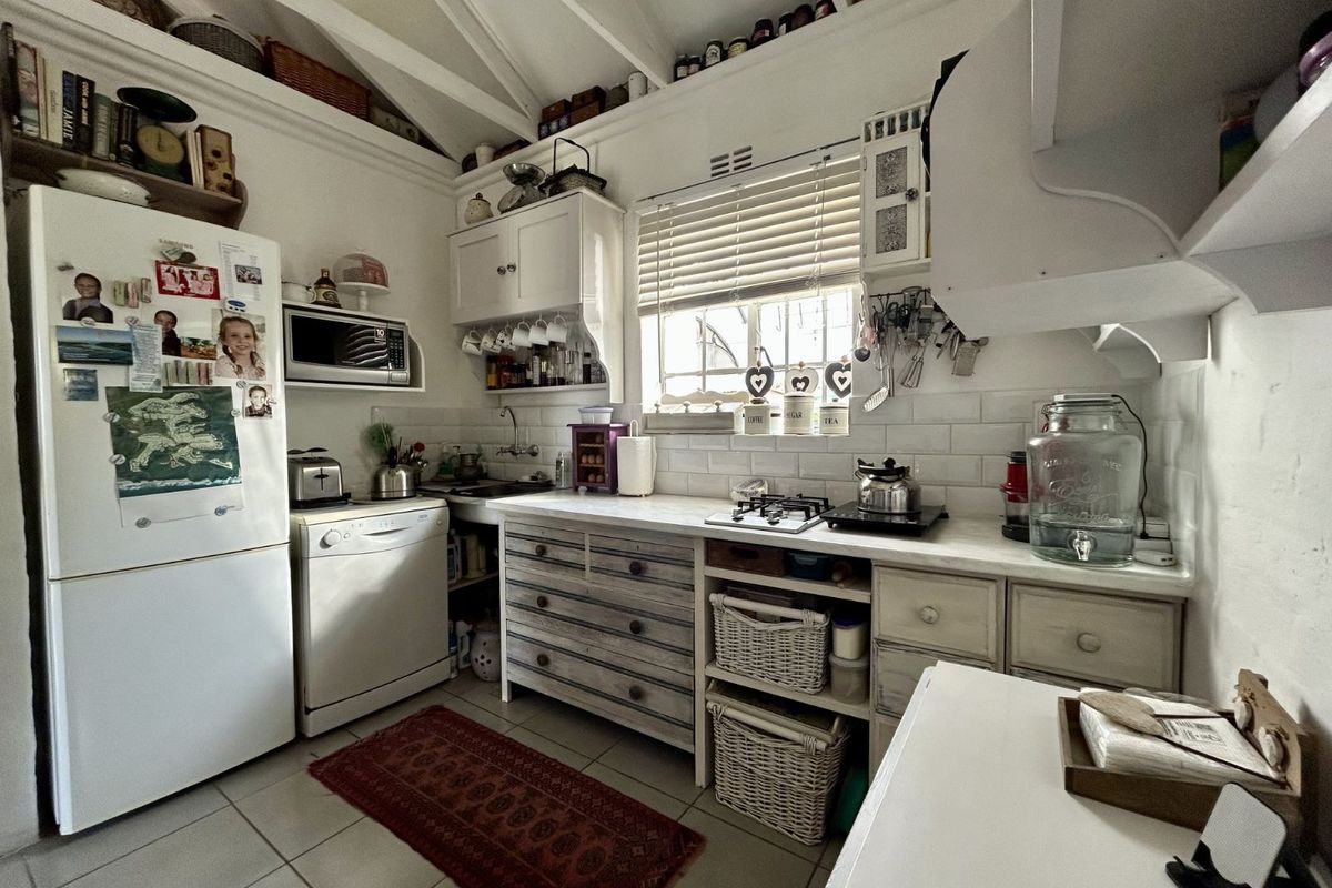 A compact, character-filled kitchen featuring white subway tile backsplash, exposed vaulted ceiling beams, and custom cabinetry with integrated storage solutions.