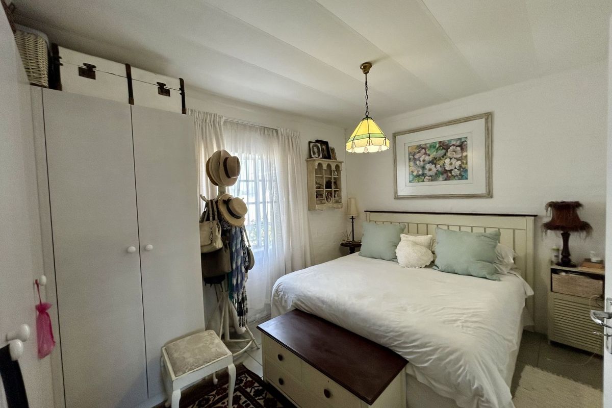 A cozy bedroom featuring built-in wardrobe cabinetry, a window with curtains, and a central pendant light fixture.