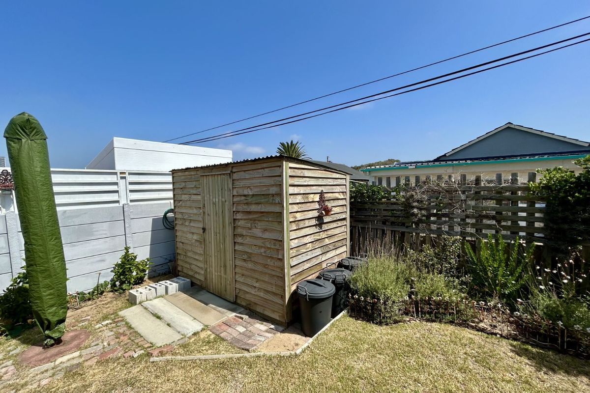 A functional timber garden shed situated in a backyard setting, featuring a corrugated roof and adjacent paved area.