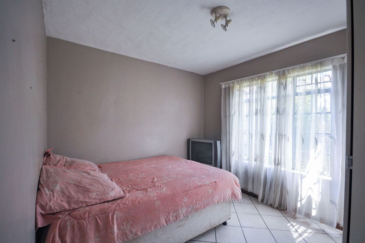 A bedroom featuring tiled flooring and a large window with natural light, providing a functional space ready for cosmetic updates.