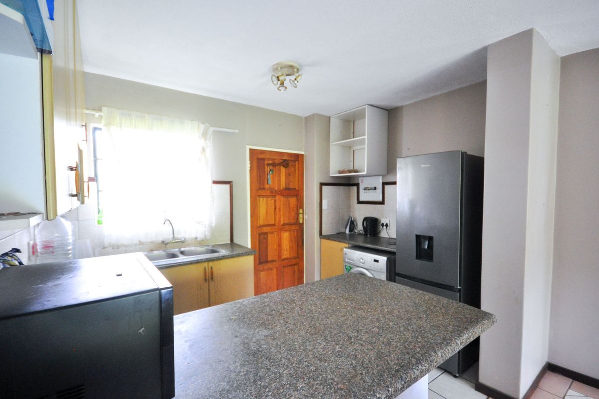 Functional kitchen featuring granite-look countertops, double basin sink, built-in cabinetry, and space for major appliances, providing a practical layout for daily meal preparation.