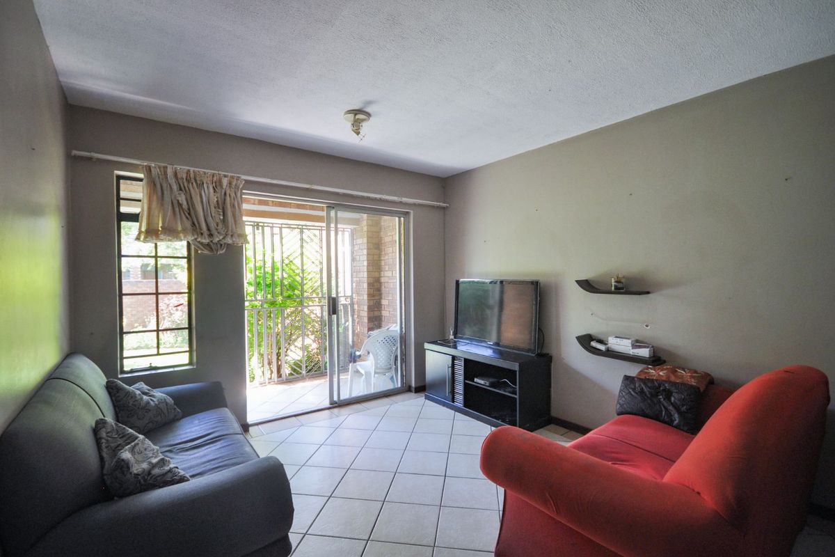 A living room featuring tiled flooring, sliding glass doors leading to a patio, and built-in wall shelving.