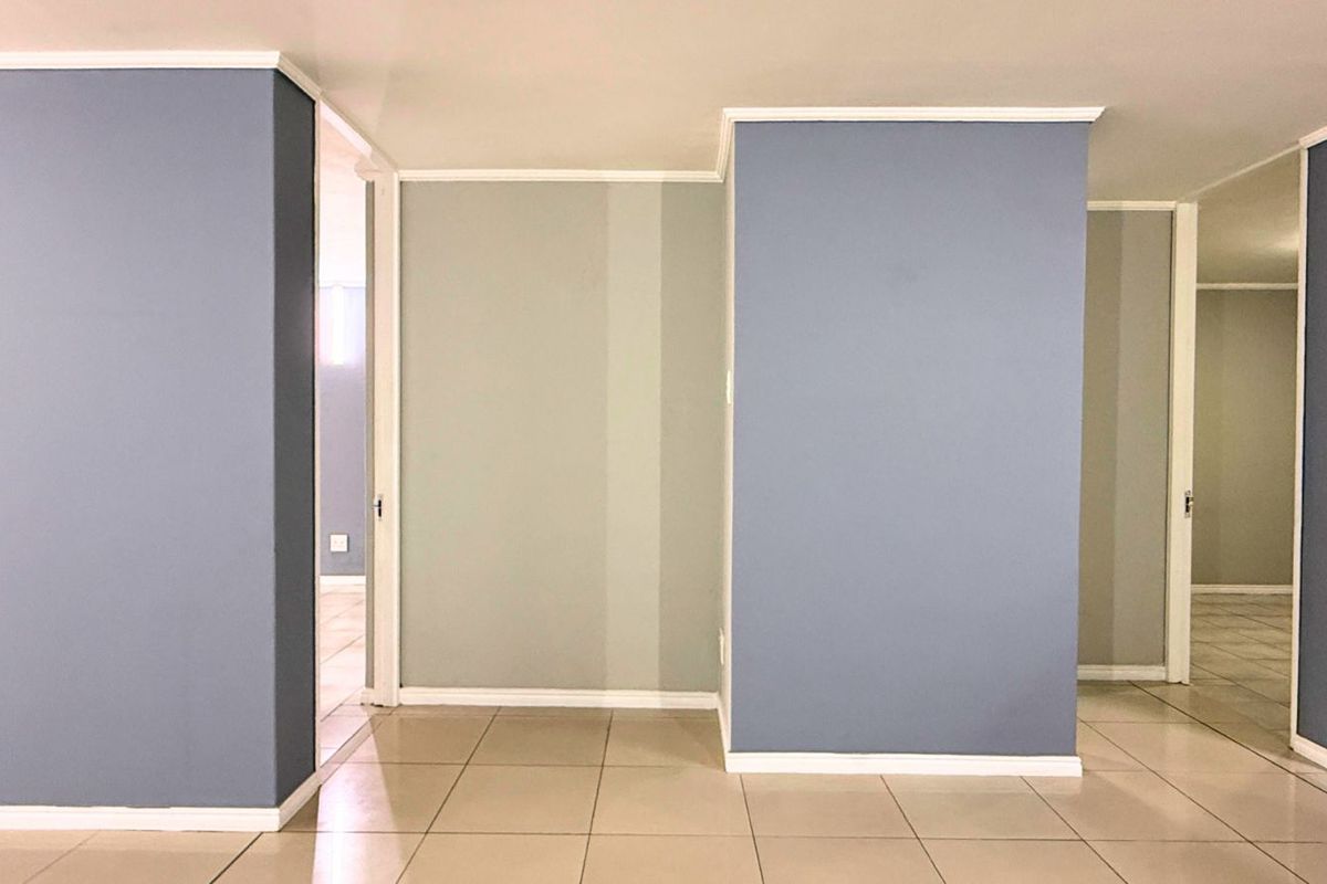 An empty interior space featuring tiled flooring, painted walls with crown molding, and multiple doorways leading to adjacent rooms.