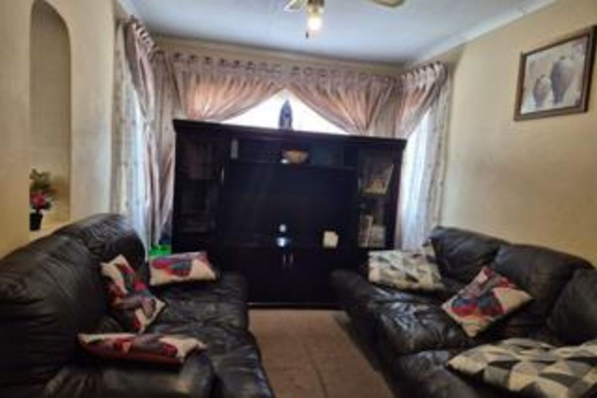 A traditional living room featuring a bay window with curtains, a ceiling fan, and an arched wall niche.