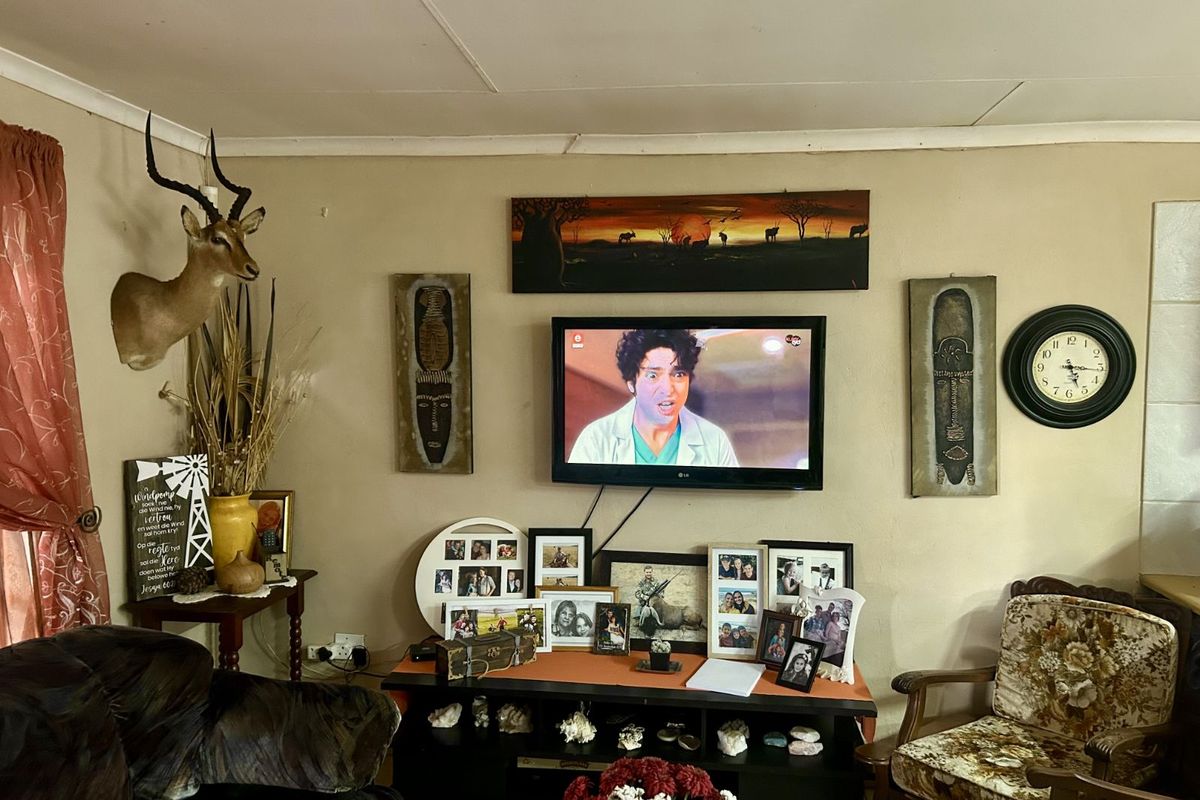 A living room featuring a wall-mounted television, tiled flooring, and standard ceiling finishes.