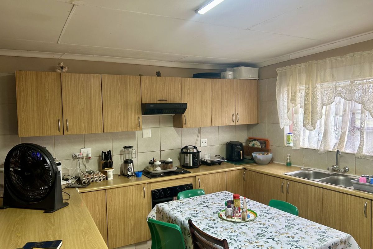 Functional kitchen featuring wood-look cabinetry, tiled splashbacks, double basin sink, and integrated oven with extractor fan.