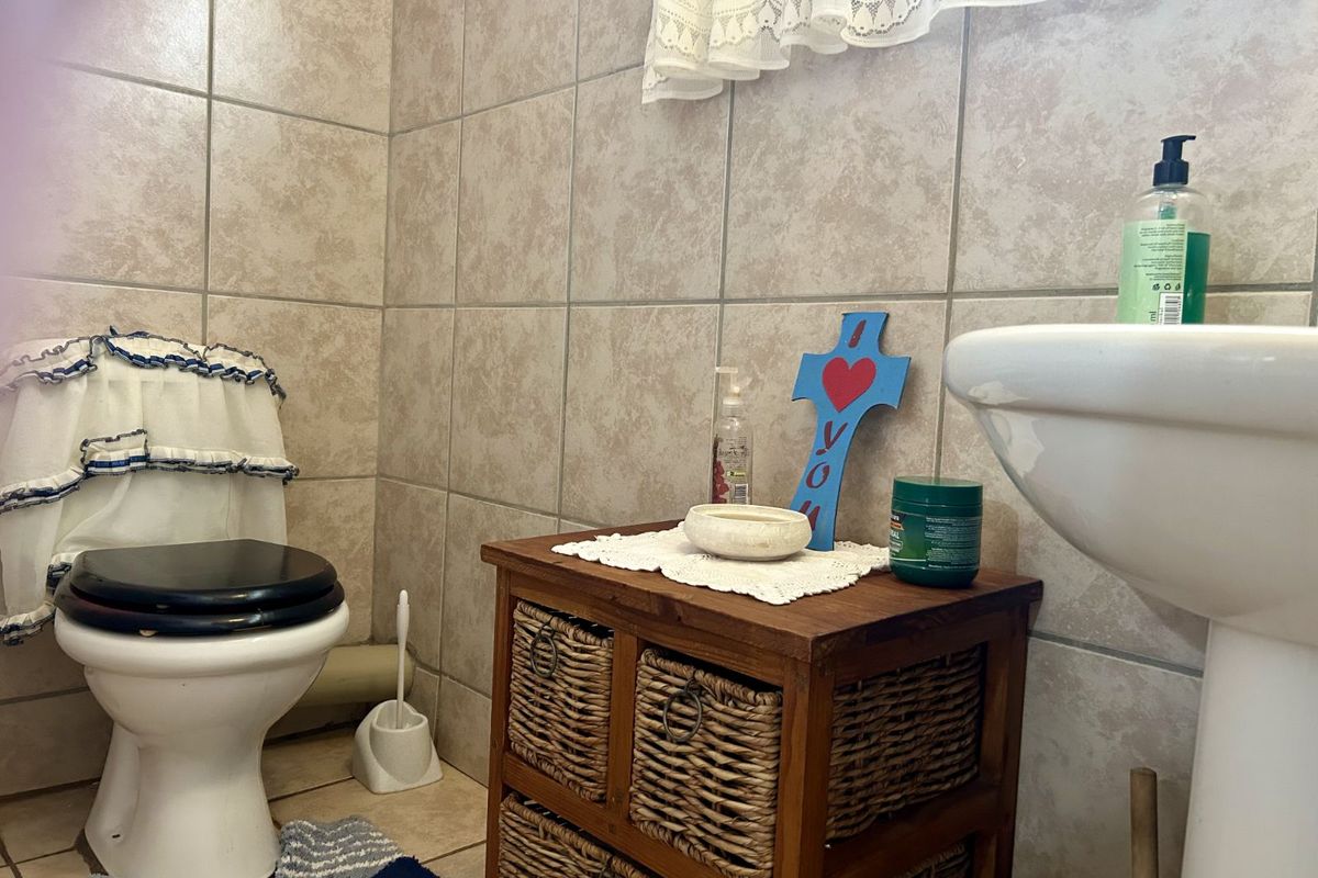 A functional bathroom featuring ceramic wall tiling, a pedestal basin, and a standard toilet suite.