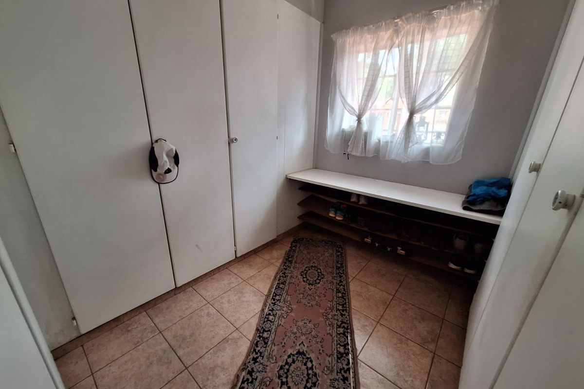 A functional dressing area or walk-in closet featuring built-in floor-to-ceiling cabinetry and a dedicated shoe storage shelf beneath the window.