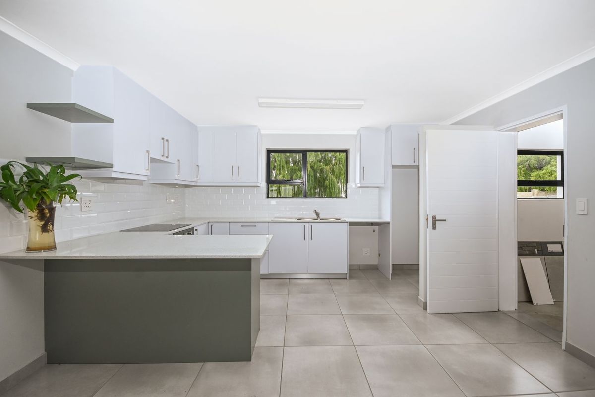 Modern kitchen featuring white cabinetry, stone countertops, subway tile backsplash, and large format floor tiles with an open-plan layout.