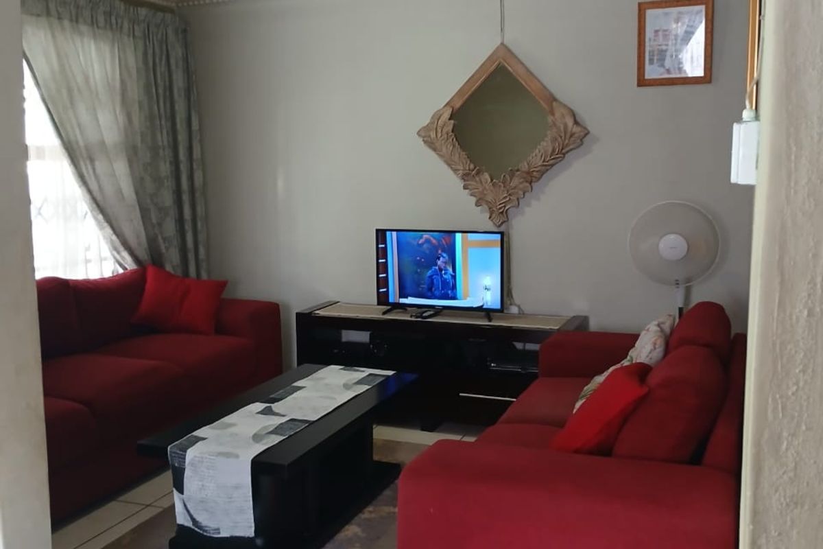 A comfortable living room featuring tiled flooring and a panelled ceiling, providing a functional space for relaxation.