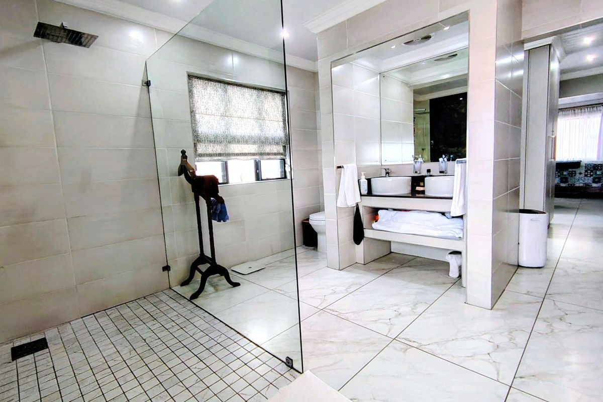 Modern bathroom featuring a large walk-in glass shower, dual vanity with vessel sinks, and polished marble-look floor tiles.