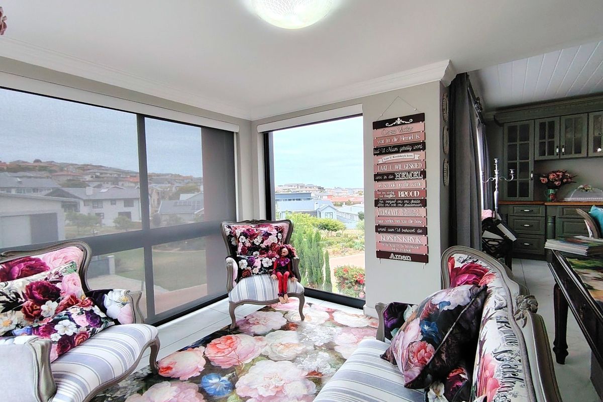 A bright living area featuring large floor-to-ceiling windows with expansive neighbourhood views, crown molding, and tiled flooring.