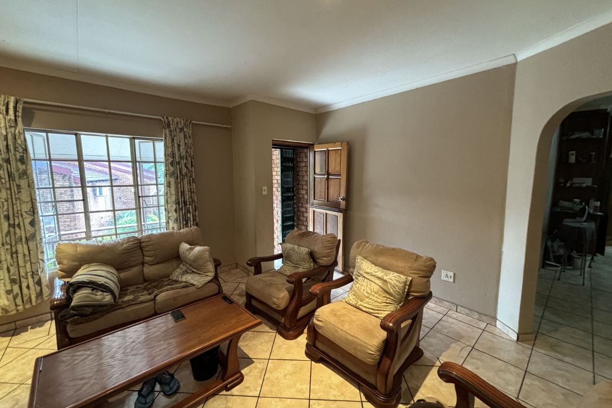 A living room featuring tiled flooring, an arched entryway, and a door leading to an exterior area.