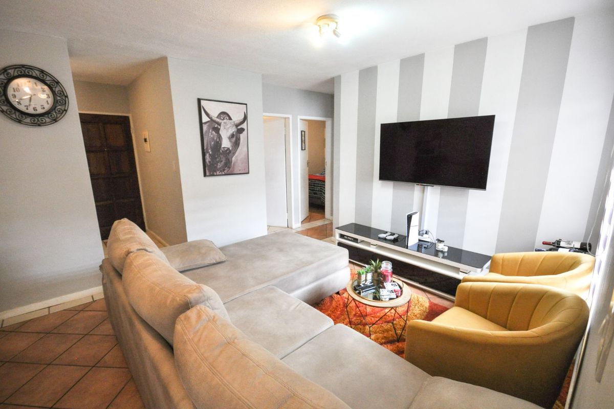 A comfortable living room featuring tiled flooring, a feature wall with vertical stripes, and a wall-mounted television setup.