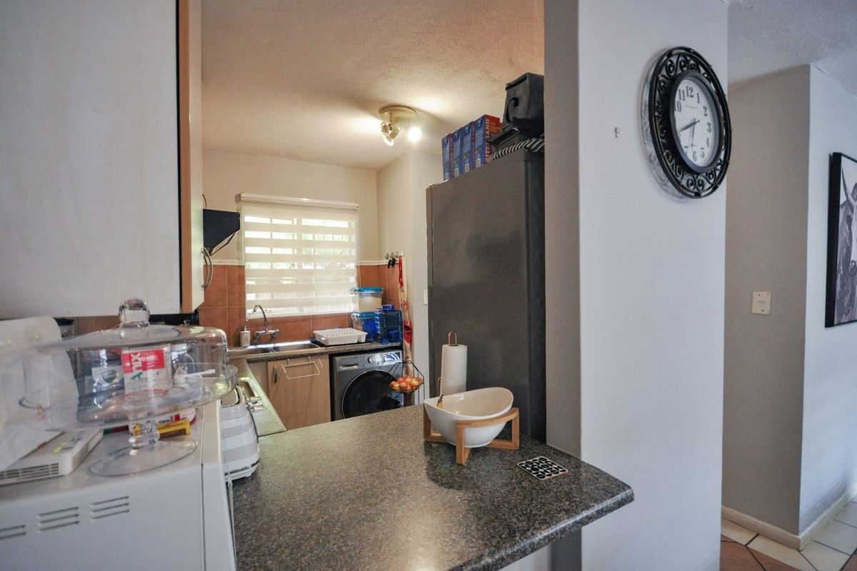 A functional kitchen featuring a breakfast bar, laminate countertops, tiled backsplash, and integrated space for laundry appliances.