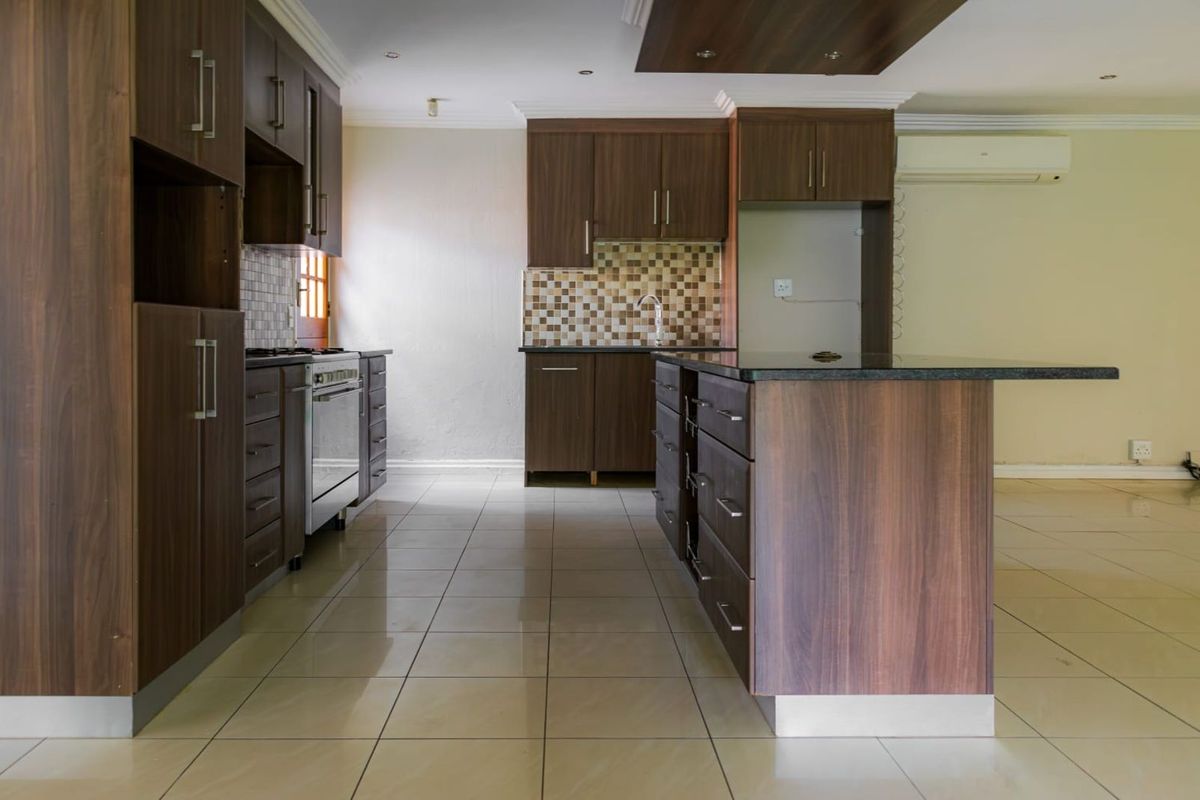 Modern kitchen featuring dark wood cabinetry, a central island with stone countertop, tiled flooring, and a built-in oven with extractor fan.