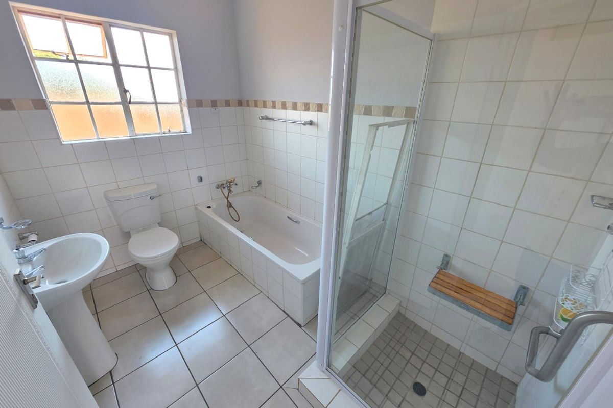 A functional bathroom featuring a pedestal basin, a standard bathtub, and a separate shower enclosure with a built-in seat.