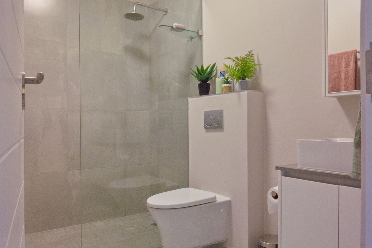 Modern bathroom featuring a frameless glass walk-in shower, wall-mounted toilet with concealed cistern, and a sleek vanity unit.