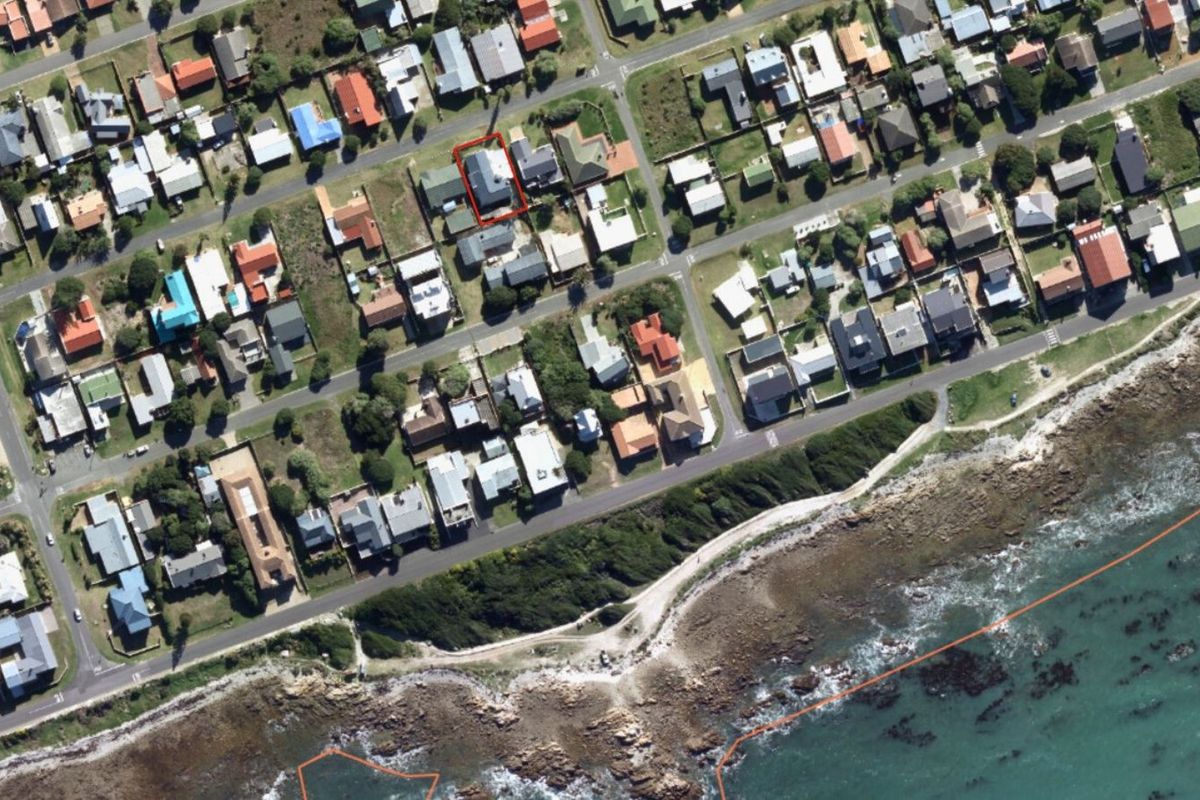 Aerial view of the coastal residential property highlighted in red, showcasing its proximity to the ocean and surrounding neighborhood layout.