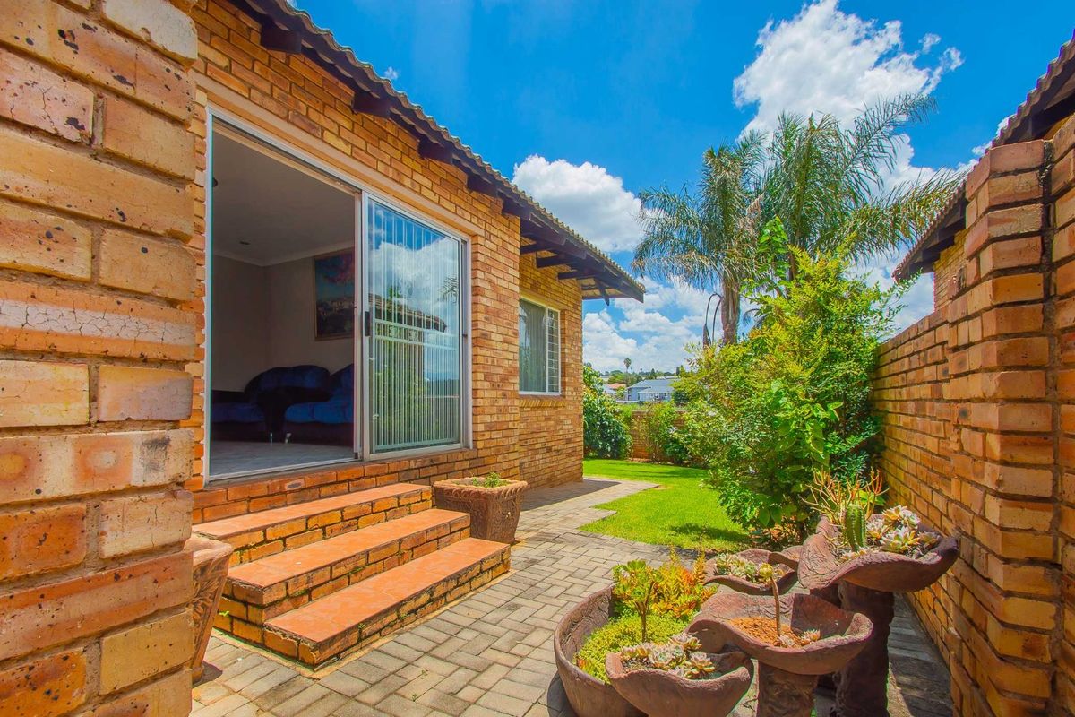 A private rear garden featuring brick paving, a small set of steps leading to a sliding glass door, and established perimeter brick walls.