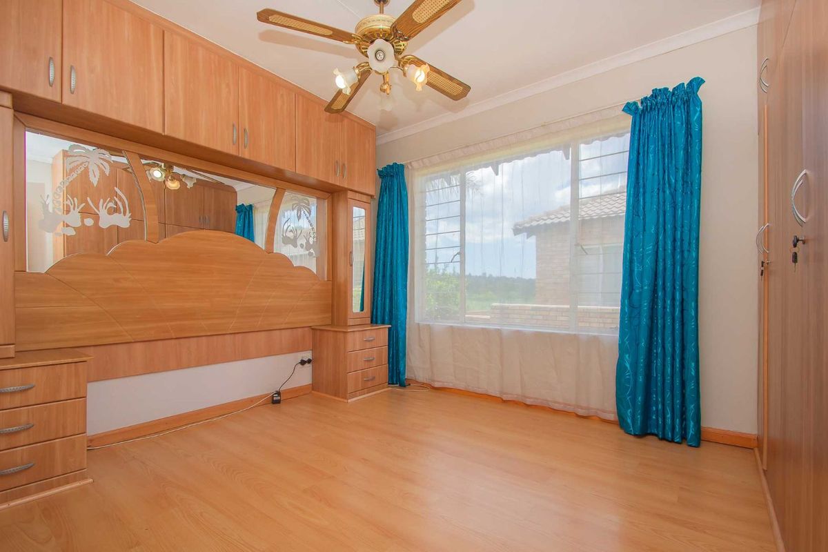 A bedroom featuring built-in wooden cabinetry, a ceiling fan, and large windows with natural light.