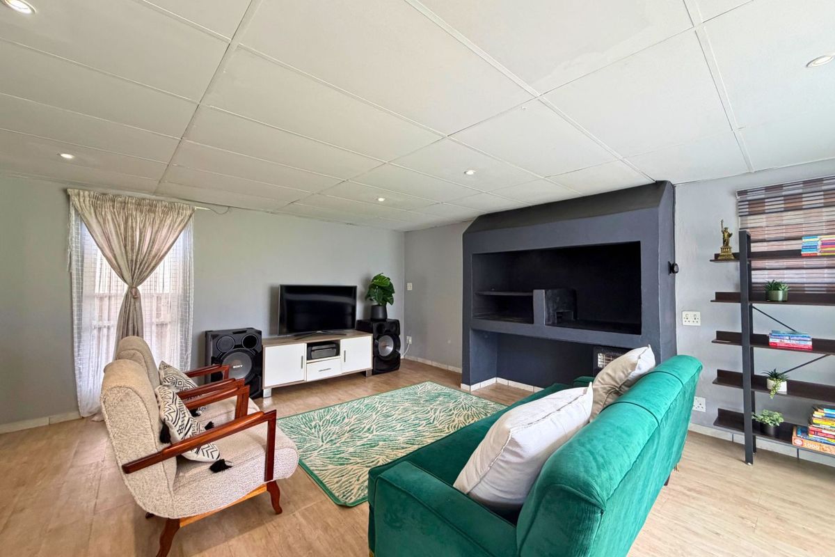 A living room featuring a built-in fireplace, recessed downlighting, and wood-look flooring, providing a functional and comfortable space for relaxation.