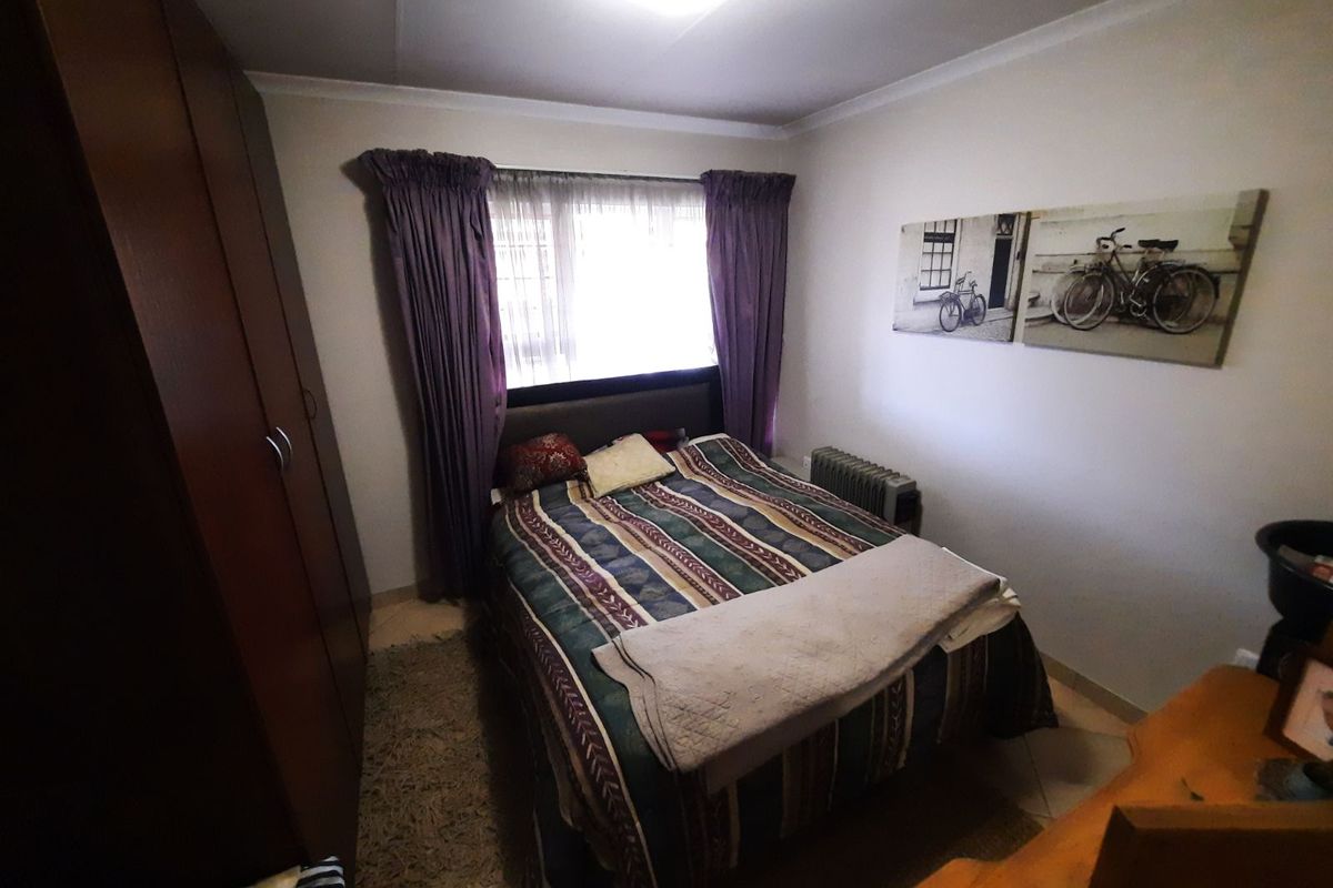 A functional bedroom featuring built-in cupboards and tiled flooring, providing a practical and comfortable living space.