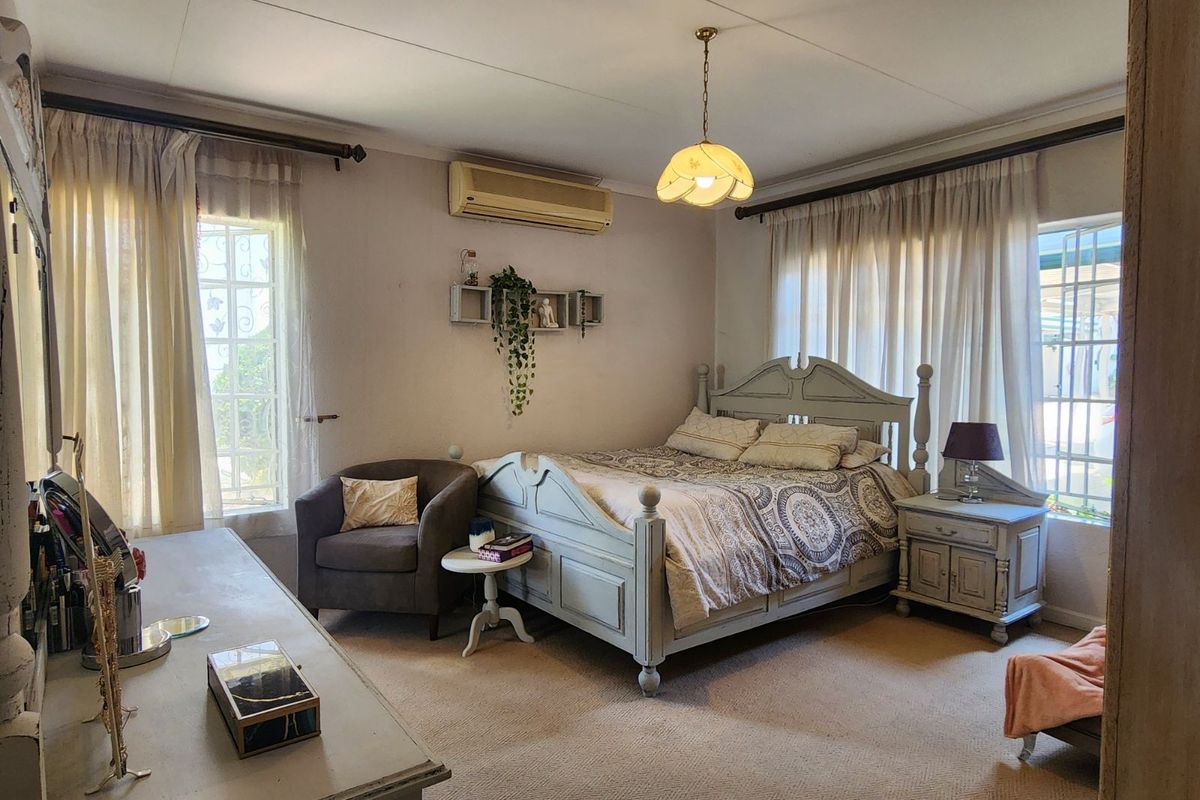 A spacious bedroom featuring carpeted flooring, large windows with curtains, and a wall-mounted air conditioning unit.