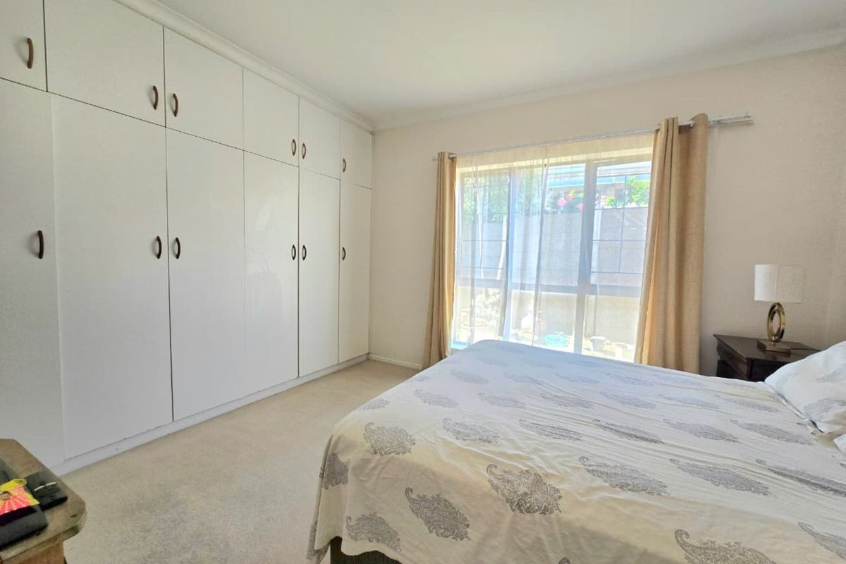 A well-lit bedroom featuring extensive floor-to-ceiling built-in cupboards and large windows that provide natural light.