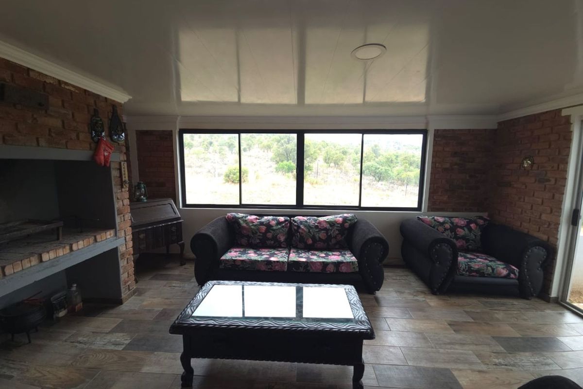 Spacious living area featuring exposed brick walls, a built-in indoor fireplace, large windows with natural views, and tiled flooring.