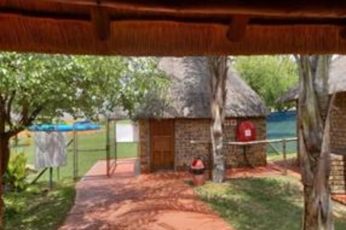 Exterior view of a rustic farm-style cottage featuring traditional thatch roofing, brick masonry, and a paved walkway leading to the entrance.