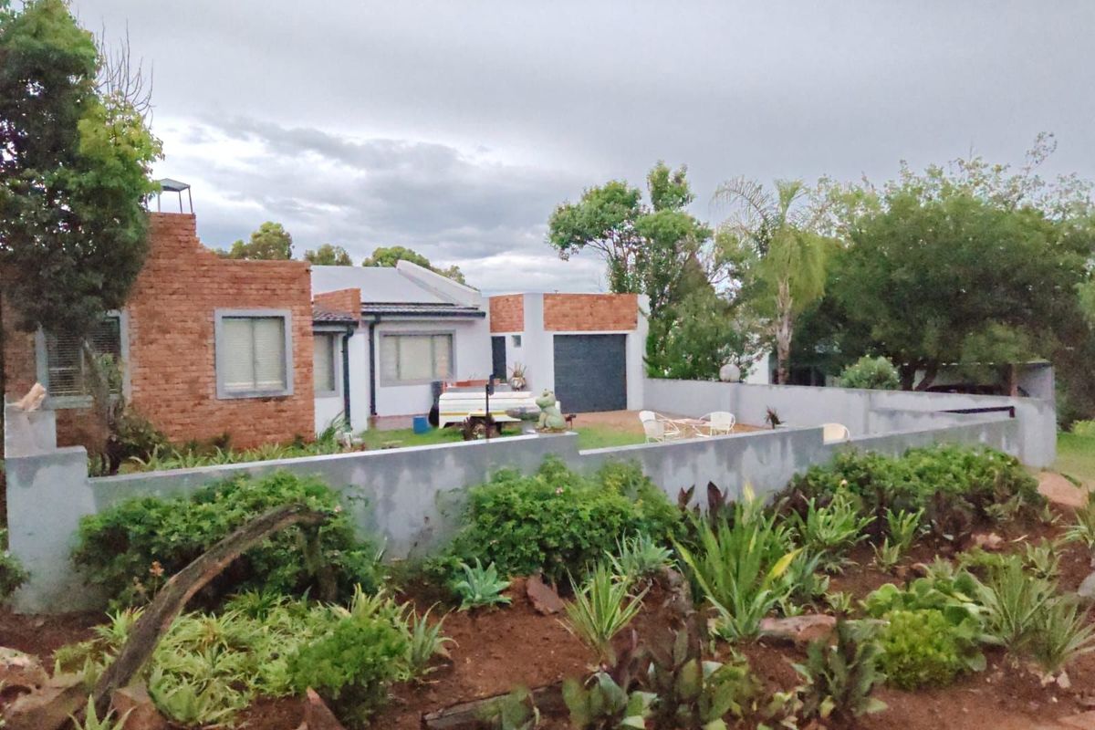 A view of the rear exterior of the townhouse, featuring exposed brickwork, a garage, and a landscaped garden area with a boundary wall.