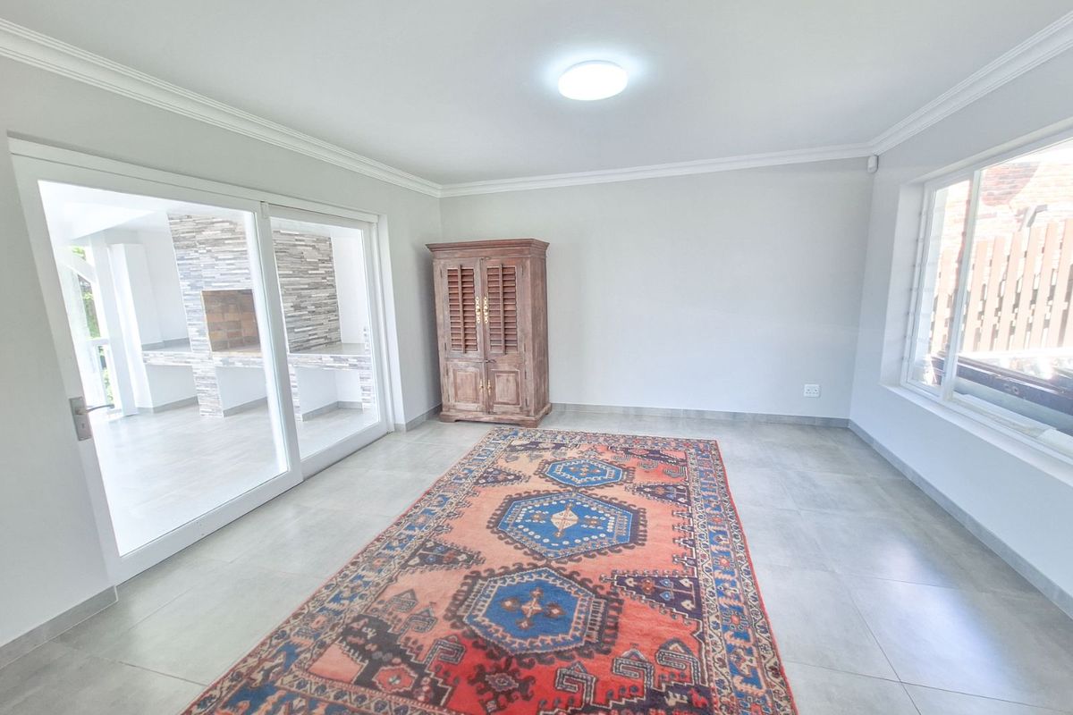Spacious living area featuring large format floor tiles, crown molding, and sliding glass doors providing seamless access to an outdoor patio area.