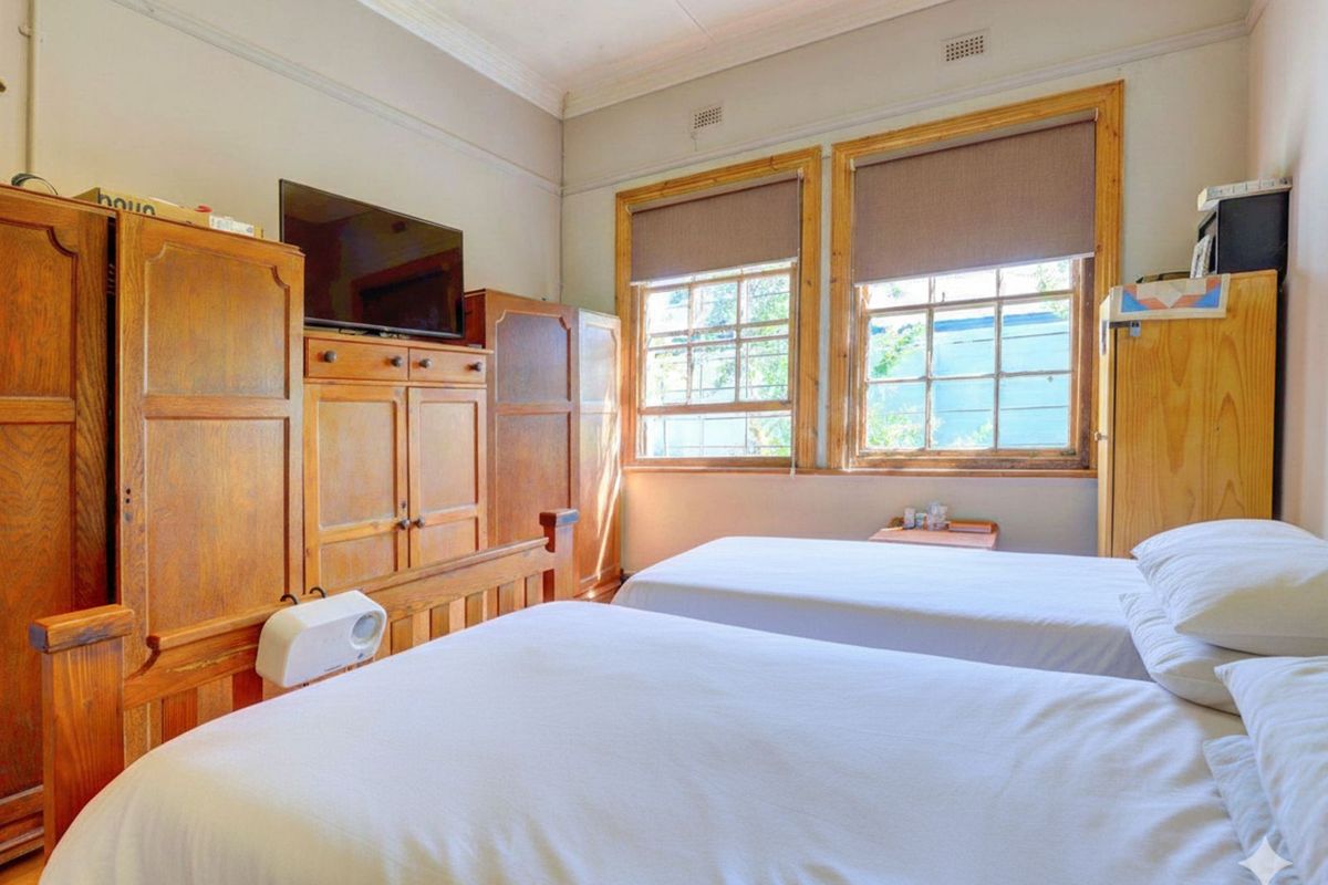 A bedroom featuring timber-framed sash windows, high ceilings with decorative cornicing, and built-in timber cabinetry.