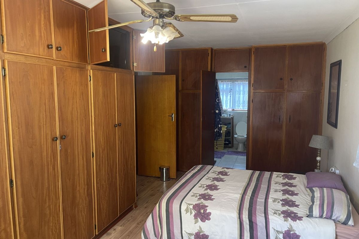 Bedroom featuring extensive built-in wooden cabinetry, a ceiling fan, and direct access to an en-suite bathroom.