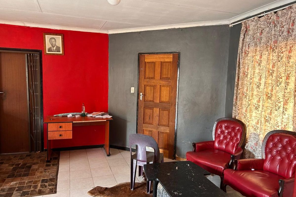 A living room area featuring tiled flooring, a wooden door, and contrasting red and grey painted walls.