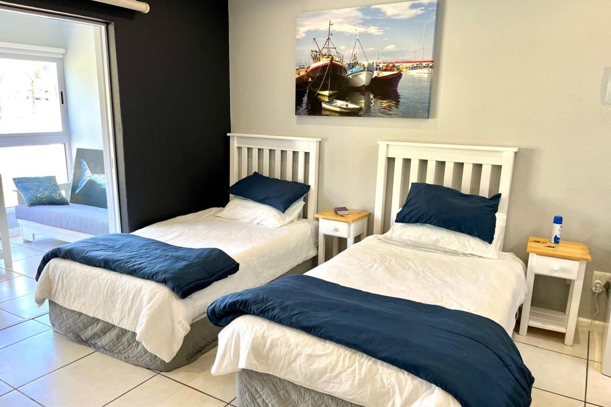 A well-maintained bedroom featuring tiled flooring, a contrasting black accent wall, and direct access to an adjoining balcony area.