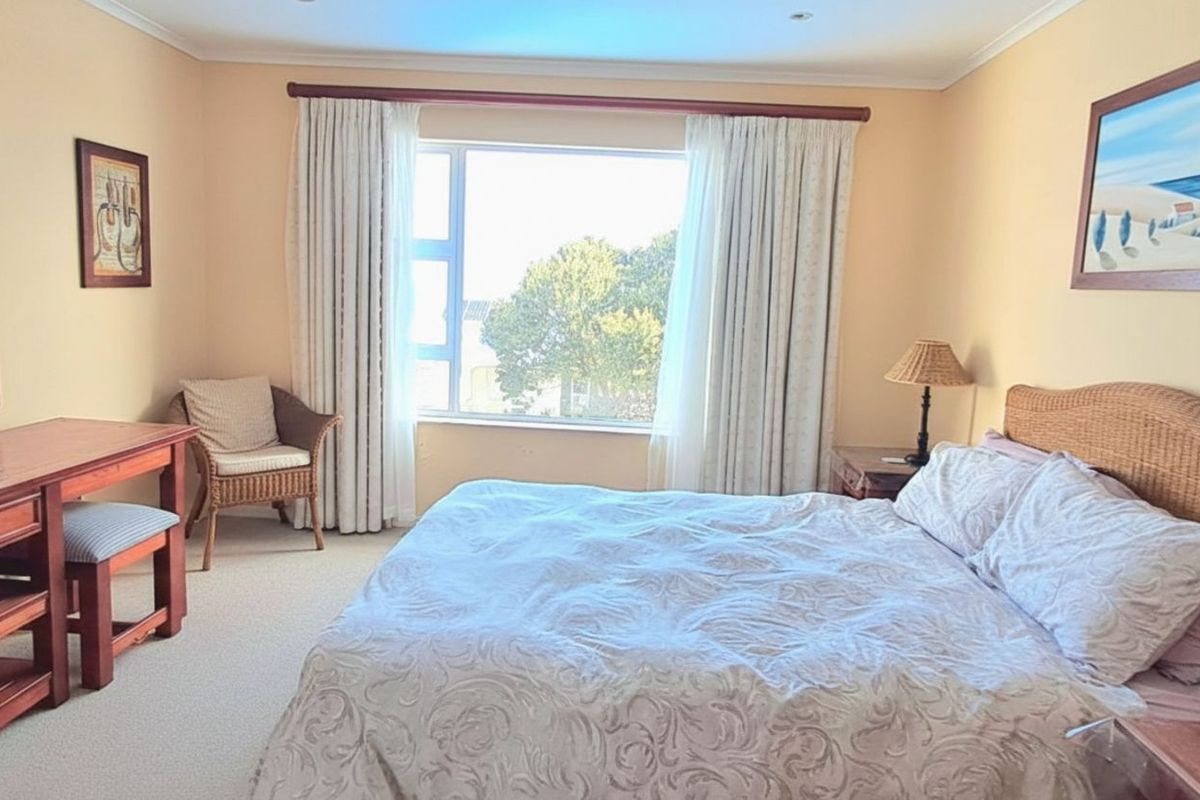 A well-lit bedroom featuring neutral carpeting, large window with curtain track, and recessed ceiling lighting.