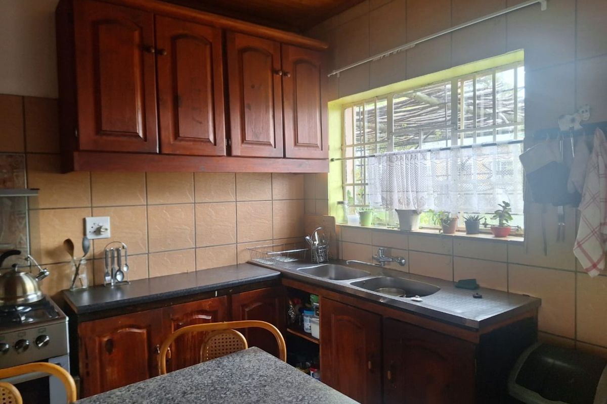 A functional kitchen featuring wooden cabinetry, tiled splashbacks, a double basin sink, and a timber-clad ceiling.