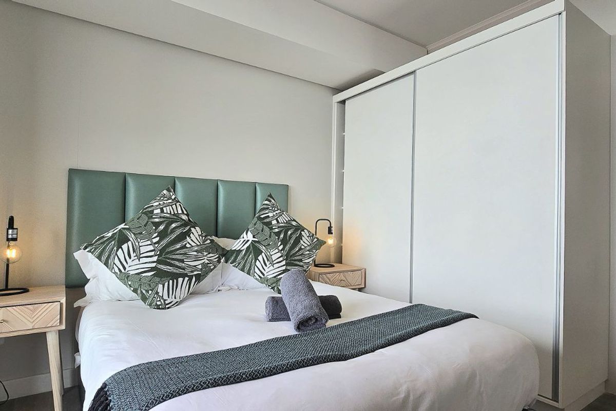 A well-maintained bedroom featuring a built-in wardrobe and an en-suite bathroom with a modern vanity.