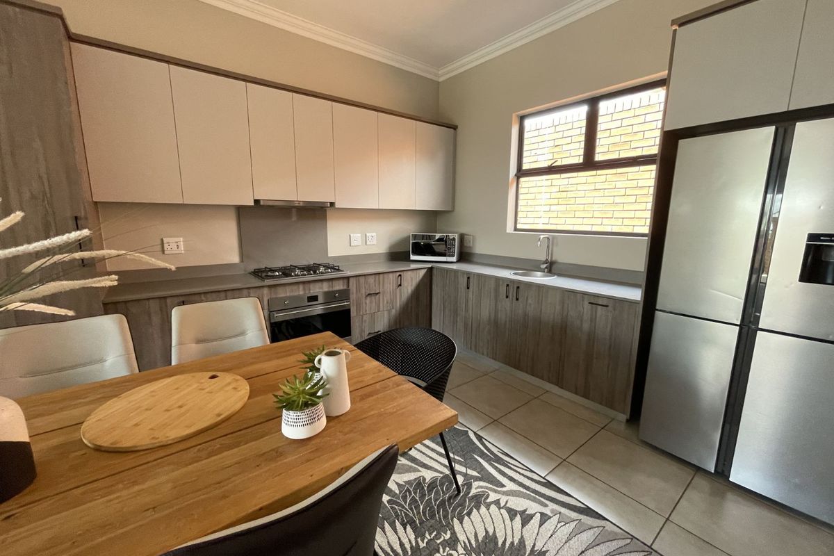 Modern kitchen featuring two-tone cabinetry, integrated gas hob, built-in oven, extractor fan, and a stainless steel sink with tiled flooring.